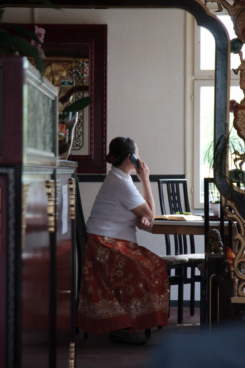 A woman chats on the phone as she sits by a table in her Thai restaurant in Switzerland
